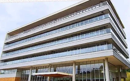 Fachada do Elume Park: edifício de cinco pavimentos com lajes em balanço, varandas de vidro e pilares cilíndricos no térreo.