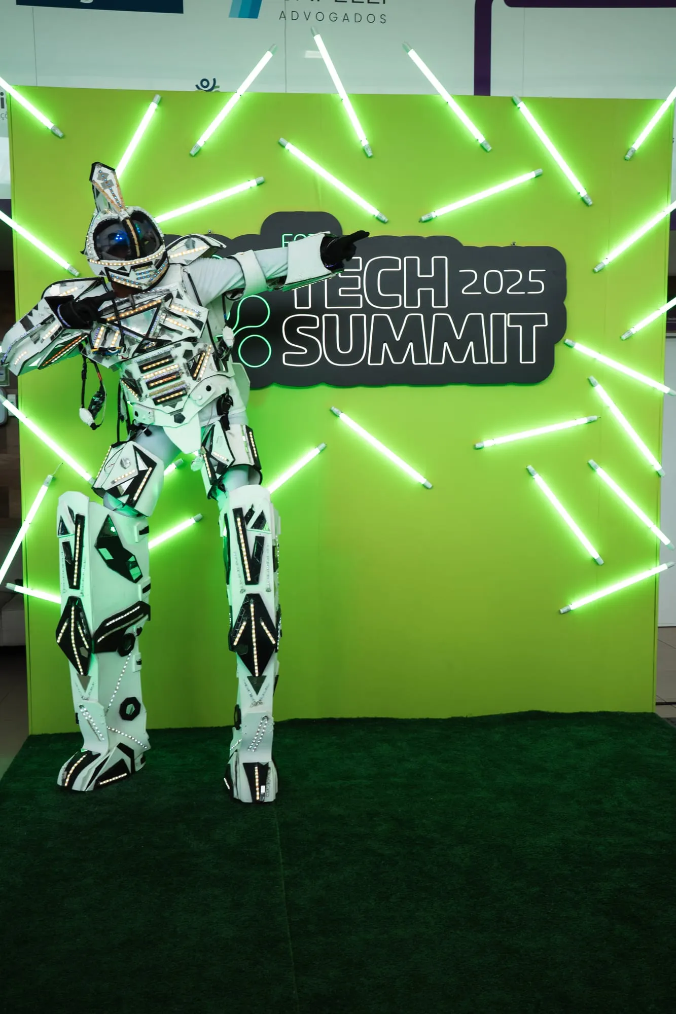 Robô de LED em frente ao painel iluminado do Tech Summit 2025